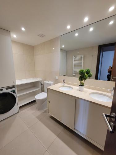 a bathroom with two sinks and a toilet and a mirror at Health Village Apartments in Cascais
