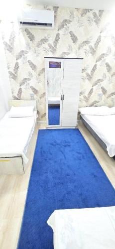 a room with two beds and a blue carpet at ARZON Halal Hotel in Tashkent