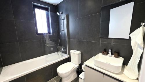 a bathroom with a white toilet and a sink at Spacious & Modern - Best Larnaca Location in Larnaca