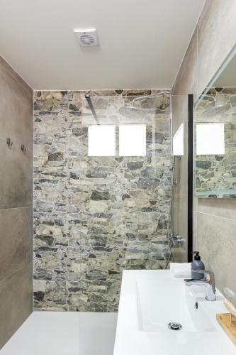 a bathroom with a sink and a stone wall at Modern Sea View Apartment Near Beach & Pool Puerto Rico in Puerto Rico de Gran Canaria