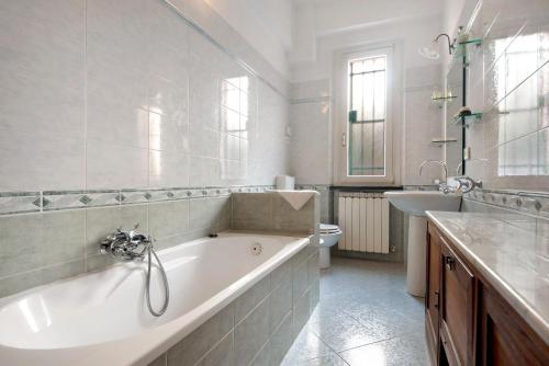 a white bathroom with a tub and a sink at Via Daneri 2 con giardino in Bonassola