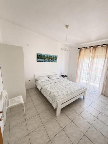 a white bedroom with a bed and a chair at Apartmani Leona in Metajna