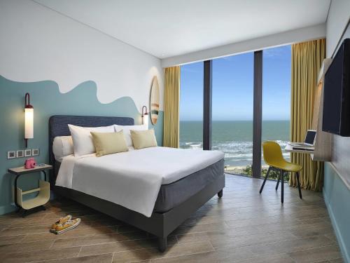 a bedroom with a bed and a view of the ocean at ibis Styles Vung Tau in Vung Tau