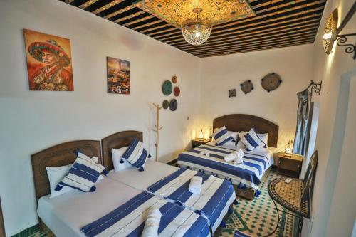 a bedroom with two beds with blue and white pillows at Riad Zayna Fes in Fez