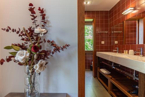 a bathroom with a sink and a vase of flowers at Quinta Trindade in Arouca