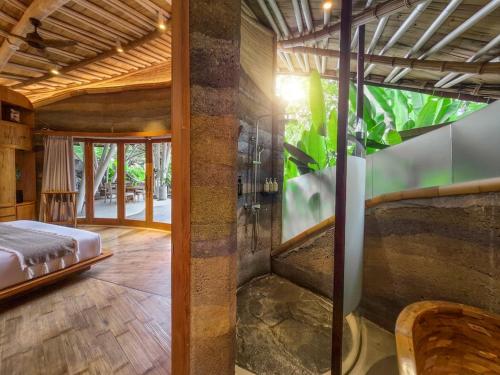 a bedroom with a bed and a glass wall at Ulaman Eco Luxury Resort in Tabanan