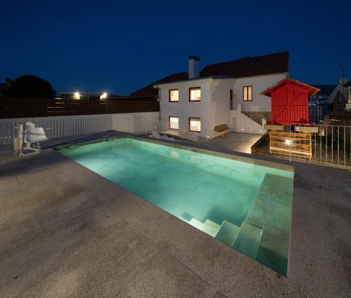 a swimming pool in front of a house at night at Apartamentos turísticos O Estaleiro in Moaña