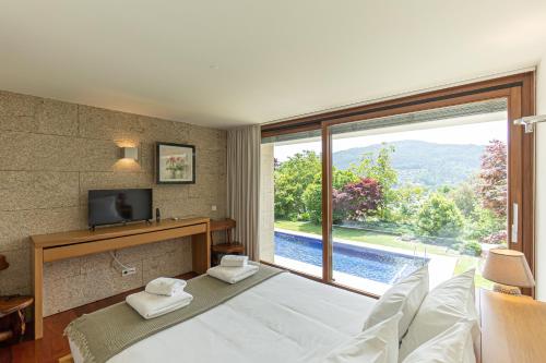 a bedroom with a bed and a large window at Quinta Trindade in Arouca