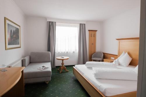 a hotel room with two beds and a chair at Hotel Martini Kaprun including free parking and Zell am See-Kaprun summer card in Kaprun