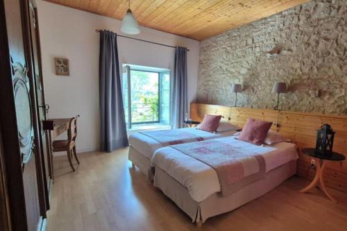a bedroom with a large bed and a stone wall at Le Tilleul de Ray in Ray-sur-Saône