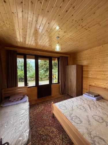 a bedroom with two beds in a wooden room at Горный коттедж in Kobuleti