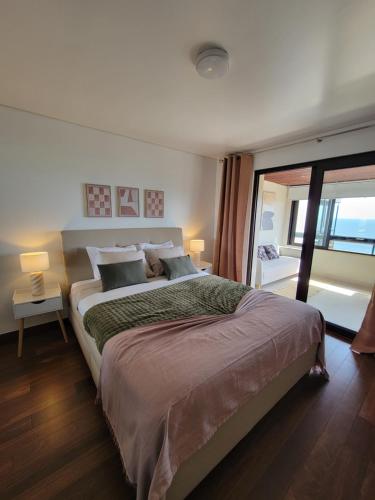 a bedroom with a large bed and a large window at Health Village Apartments in Cascais