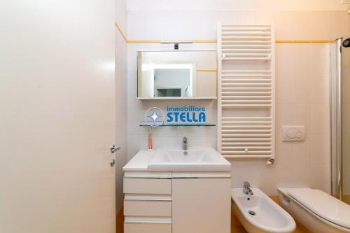a bathroom with a sink and a toilet and a mirror at Residence Maricel in Lido di Jesolo