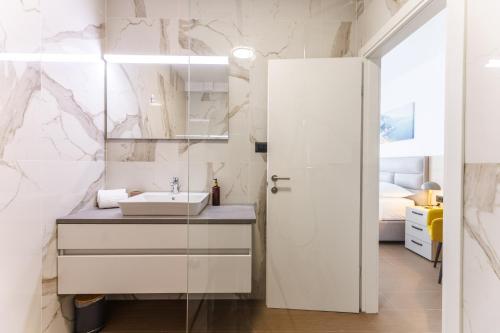 a white bathroom with a sink and a mirror at Stella Maris Beach in Podstrana