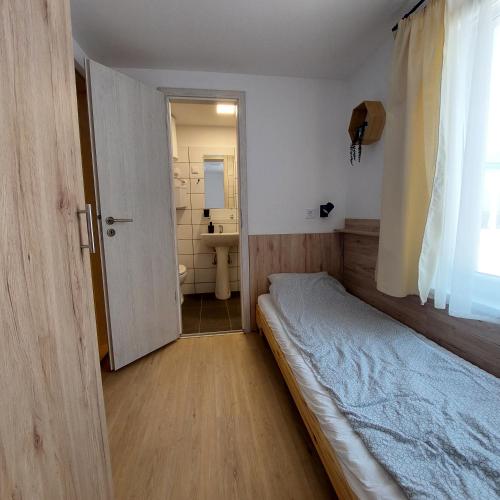 a small bedroom with a bed and a bathroom at Pájer Plázs & Resort in Gyomaendrőd