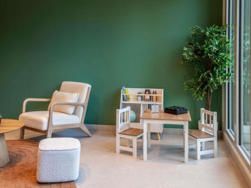 a living room with two chairs and a table and a plant at Adagio Access Paris Nanterre in Nanterre