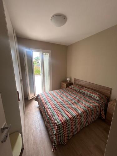 a bedroom with a bed with a plaid blanket and a window at Maiullari Holiday House in Policoro