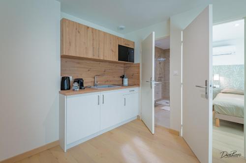 a kitchen with white cabinets and a bed in a room at Domaine de cézille-Appart hotel le Moulin du lac in Jayat