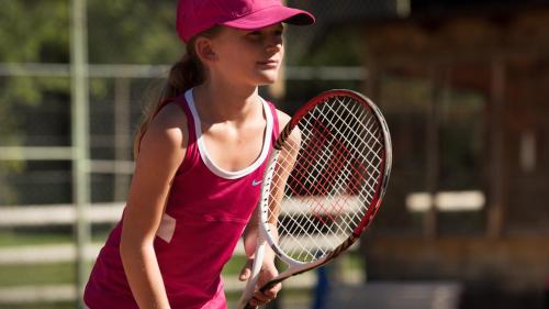 a young woman holding a tennis racket on a court at Palladium de Champéry in Champéry