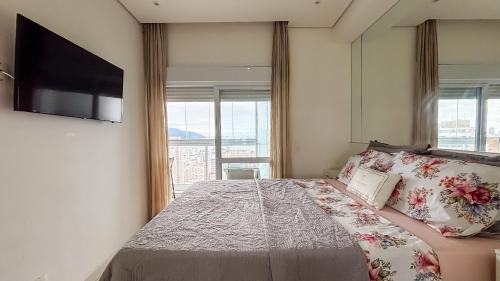 a bedroom with a large bed with a tv on the wall at SHB - Refinement, Ocean View, Sauna and Pool! in Santos