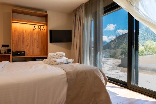 a bedroom with a bed with a large window at Montiva GuestHouse in Karpenisi