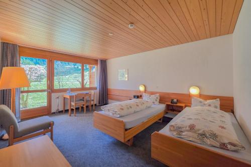 a hotel room with two beds and a table and chairs at Hotel Meielisalp in Leissigen