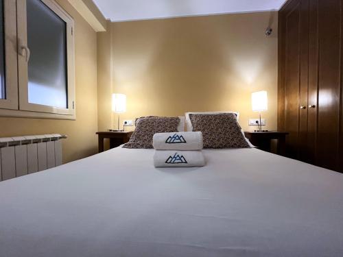 a bedroom with a large white bed with two pillows at AC Apartaments Comapedrosa Canillo in Canillo
