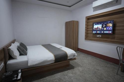 a bedroom with a bed and a tv on the wall at Hotel Subarnrekha Heritage- Lalpur, Kanke Road in Rānchī