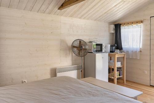 a room with a bed and a refrigerator and a fan at Chalet La Bienvenue in Vouzon