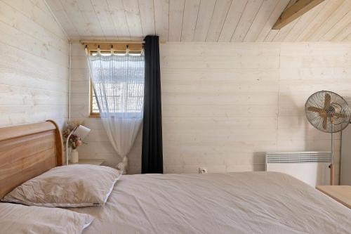 a bedroom with a bed with a window and a fan at Chalet La Bienvenue in Vouzon