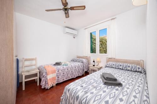 a bedroom with two beds and a window at Villa Gelabert Ametller in Cala en Bosc