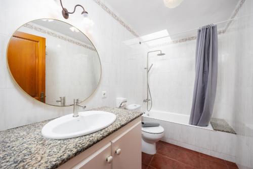 a bathroom with a sink and a mirror and a toilet at Villa Gelabert Ametller in Cala en Bosc