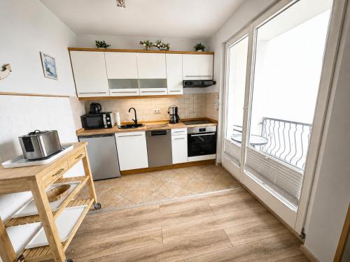a small kitchen with white cabinets and a large window at Seebad Ahlbeck - Haus MIRAMAR in Heringsdorf
