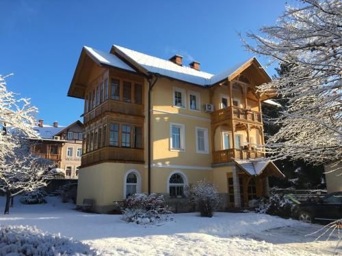 Una gran casa amarilla con nieve en el suelo en Vila Julija, en Bled