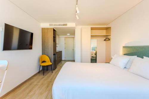a bedroom with a white bed and a yellow chair at Old Town 63 in Paphos