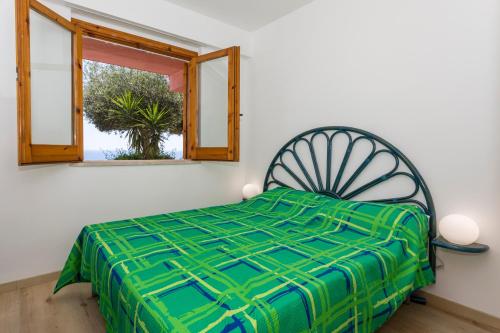 a bedroom with a green bed and a window at Paradise Residence Garden in SantʼAlessio Siculo