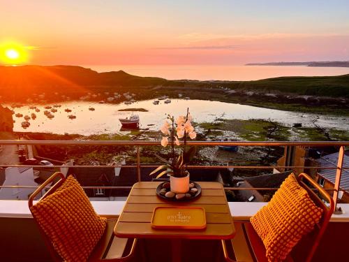 a balcony with a table and chairs and a sunset at Les Pierres Marines in Le Conquet