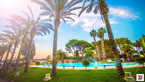 einen Pool mit Palmen und Bänken in einem Park in der Unterkunft Relais Reggia Domizia in Manduria
