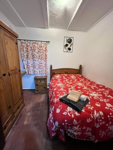 a bedroom with a red bed and a window at Casa La Ferrata in Jimera de Líbar