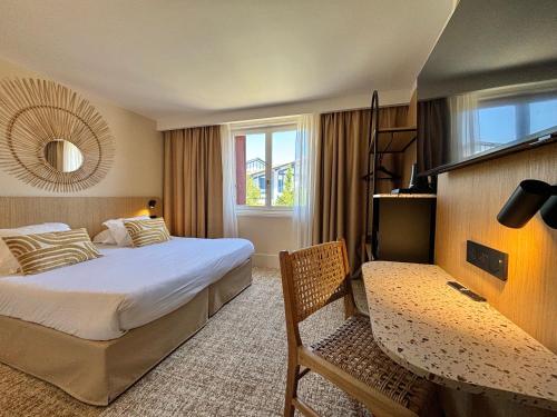 a hotel room with a bed and a table and a chair at Hôtel & Résidence Vacances Bleues Orhoïtza in Hendaye