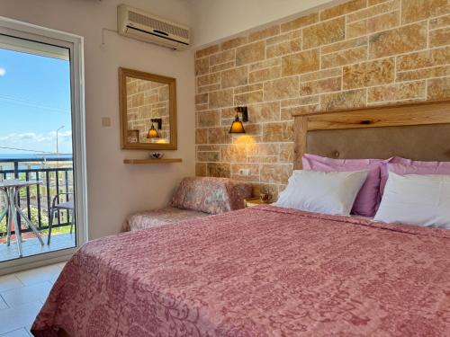a bedroom with a bed and a chair and a window at Studios Fedra in Potamiá