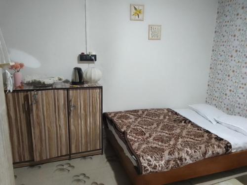 a bedroom with a bed and a wooden cabinet at Mist N Mountain in Kurseong