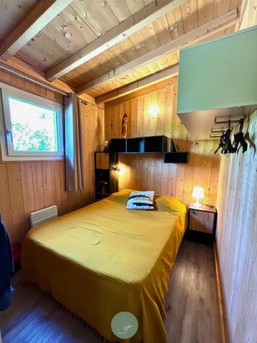 a bedroom with a large yellow bed in a room at CHALET SUR PILOTIS - 4 personnes - CLIMATISÉ- PISCINE- PROCHE PLAGE in Arès