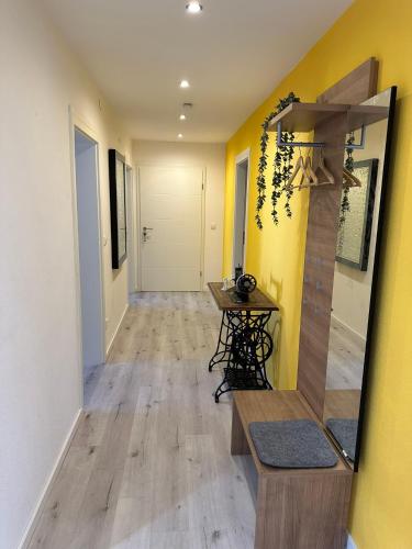 a hallway with a table and a yellow wall at Haselbach Living in Ehekirchen