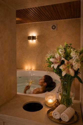a woman in a bath tub with a vase of flowers at Duque Hotel Boutique & Spa in Buenos Aires