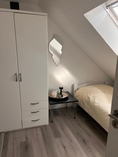 a white bedroom with a bed and a table at Gemütlichkeit im Grünen in Warendorf