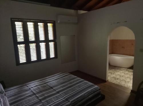 a bedroom with a tub and a bed and a window at Kaiche in Trafalgar