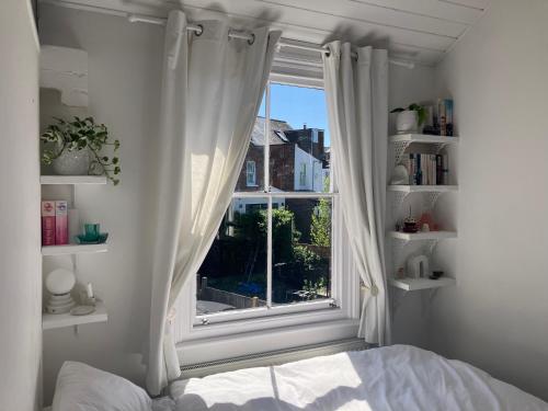 a bedroom with a window with white curtains at Beautiful City Centre Apartment with Cathedral View in St. Albans