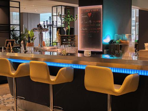a bar with yellow chairs in a restaurant at Hotel Novotel Evry Courcouronnes in Courcouronnes