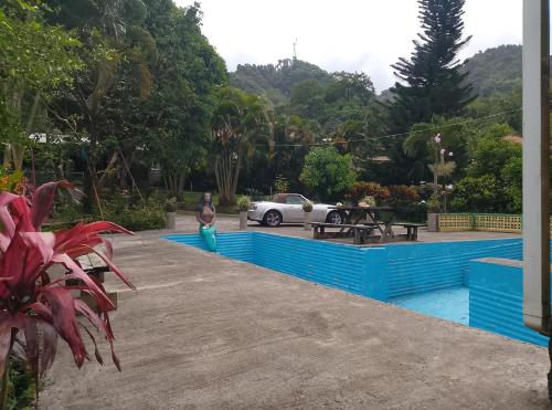 a man standing next to a swimming pool with a car at Kaiche in Trafalgar